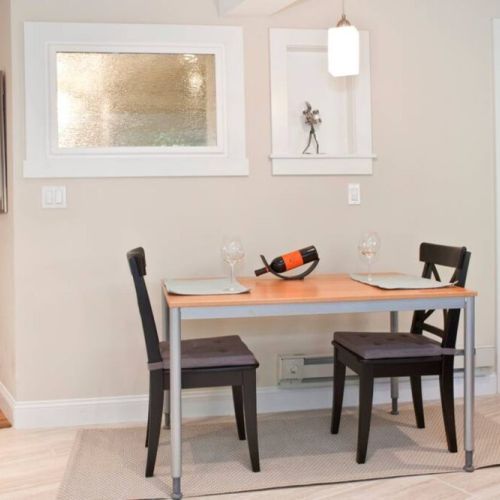 Entrance, dining table, and view of the bedroom to the right.